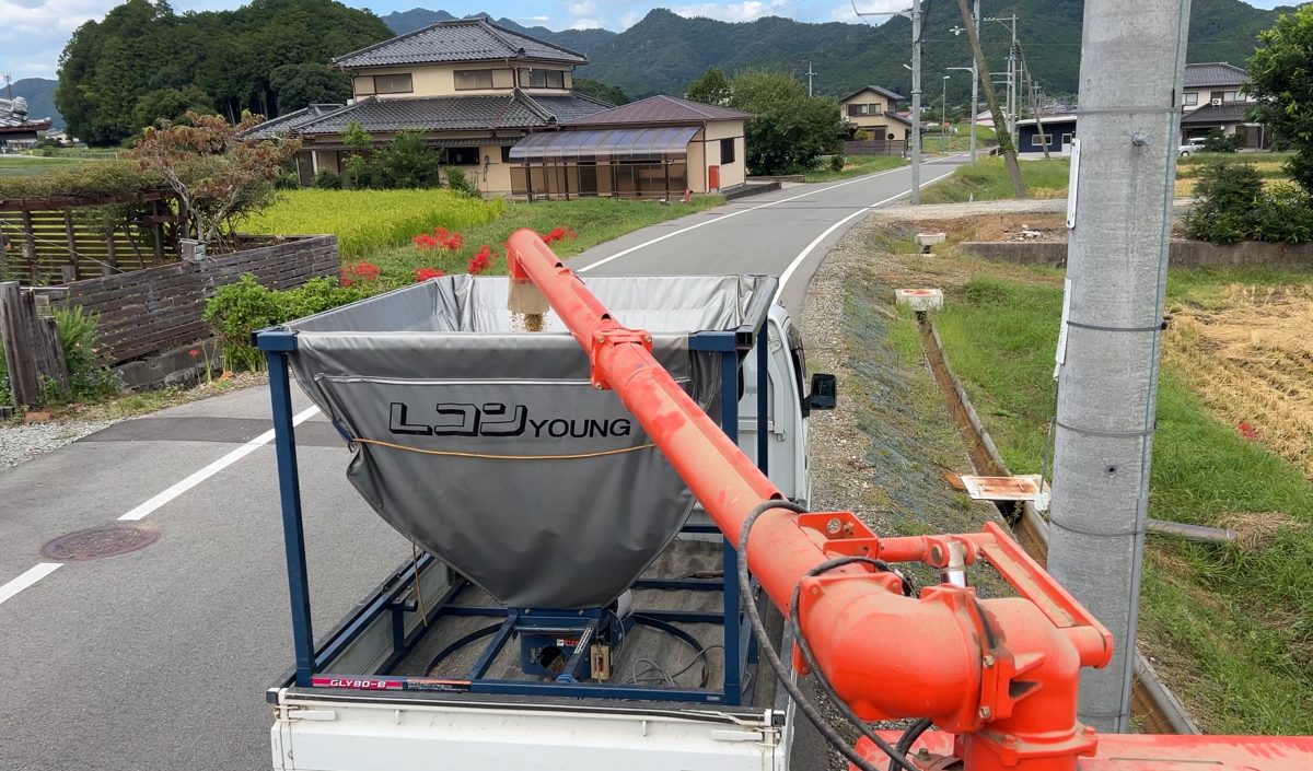 コンバインから軽トラの籾コンテナへ籾を移しているところ
